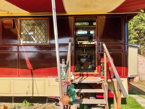 Une caravane ancienne dotée d’un coin cuisine, comprenant une cuisinière et des étagères remplies de divers objets.