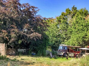 Un autobus d’époque est garé dans un espace verdoyant, avec des arbres en arrière-plan.