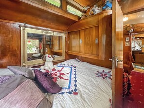 A bedroom with a large mirror, wooden wardrobe, and a bed with a quilt.