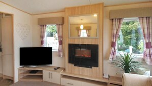 A living room with a flat-screen TV, a fireplace, and a large window with curtains. - 2 bedroom accommodation in Watchet, Somerset (Watchet, Somerset)