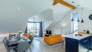 Een modern loft met een eethoek, keuken en woonruimte, met een schuine plafond en grote ramen.