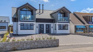 Een modern huis met twee verdiepingen, grote ramen en een stenen steunmuur ervoor.