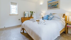 A bedroom with a bed, bedside lamps, a mirror, a window, and a painting on the wall. - 1 bedroom accommodation in Faversham (Faversham)