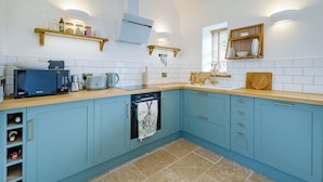 A kitchen with a microwave, toaster, and kettle on the counter, a dishwasher, and cabinets with gold handles. - 1 bedroom accommodation in Faversham (Faversham)