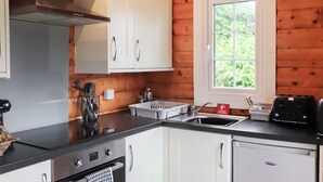 Una cocina moderna con armarios blancos, un lavamanos de acero inoxidable y un tostador.