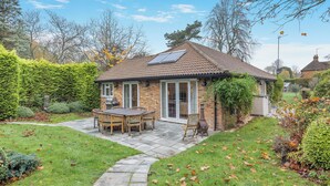 A house with a tiled roof, a patio with a table and chairs, and a garden with a stone pathway. - 2 bedroom accommodation in Penn (Penn)