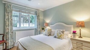 A bedroom with a large bed, two bedside lamps, a window with curtains, a radiator, and a wooden chair. - 2 bedroom accommodation in Penn (Penn)