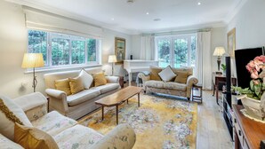 A spacious living room with two sofas, a coffee table, and a television. There are large windows providing natural light and views of greenery outside. - 2 bedroom accommodation in Penn (Penn)