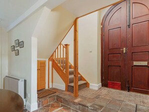 A staircase with wooden railings leading to a landing, a large wooden door, and a radiator on the wall. - The setting is peaceful yet never far from the sea. (Fishguard)