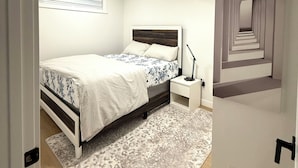 Une chambre à coucher avec un lit, une table de chevet et un mur orné d’un miroir.