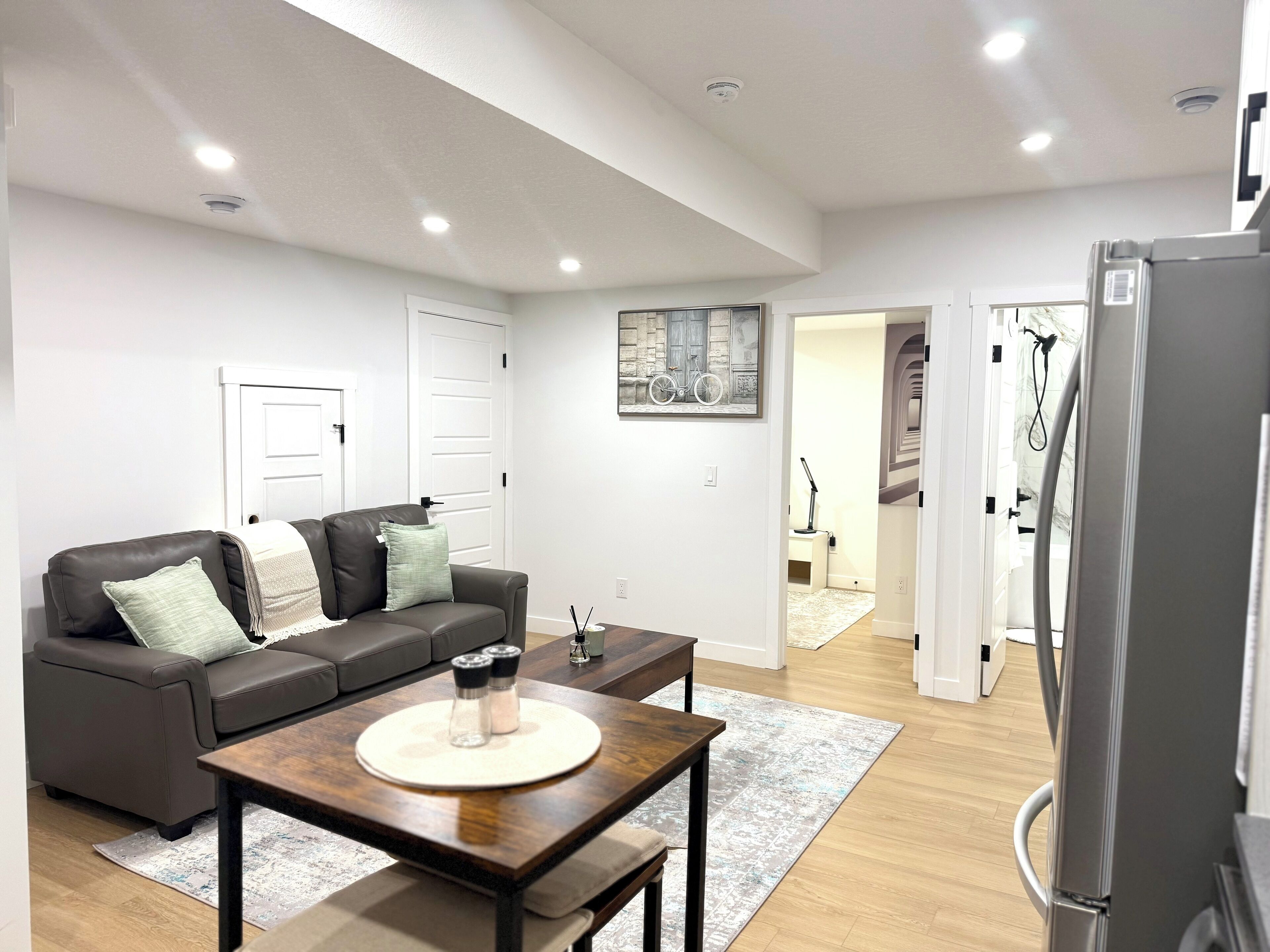 A modern living room with a dark brown leather sofa, a wooden coffee table, and a white door in the background.