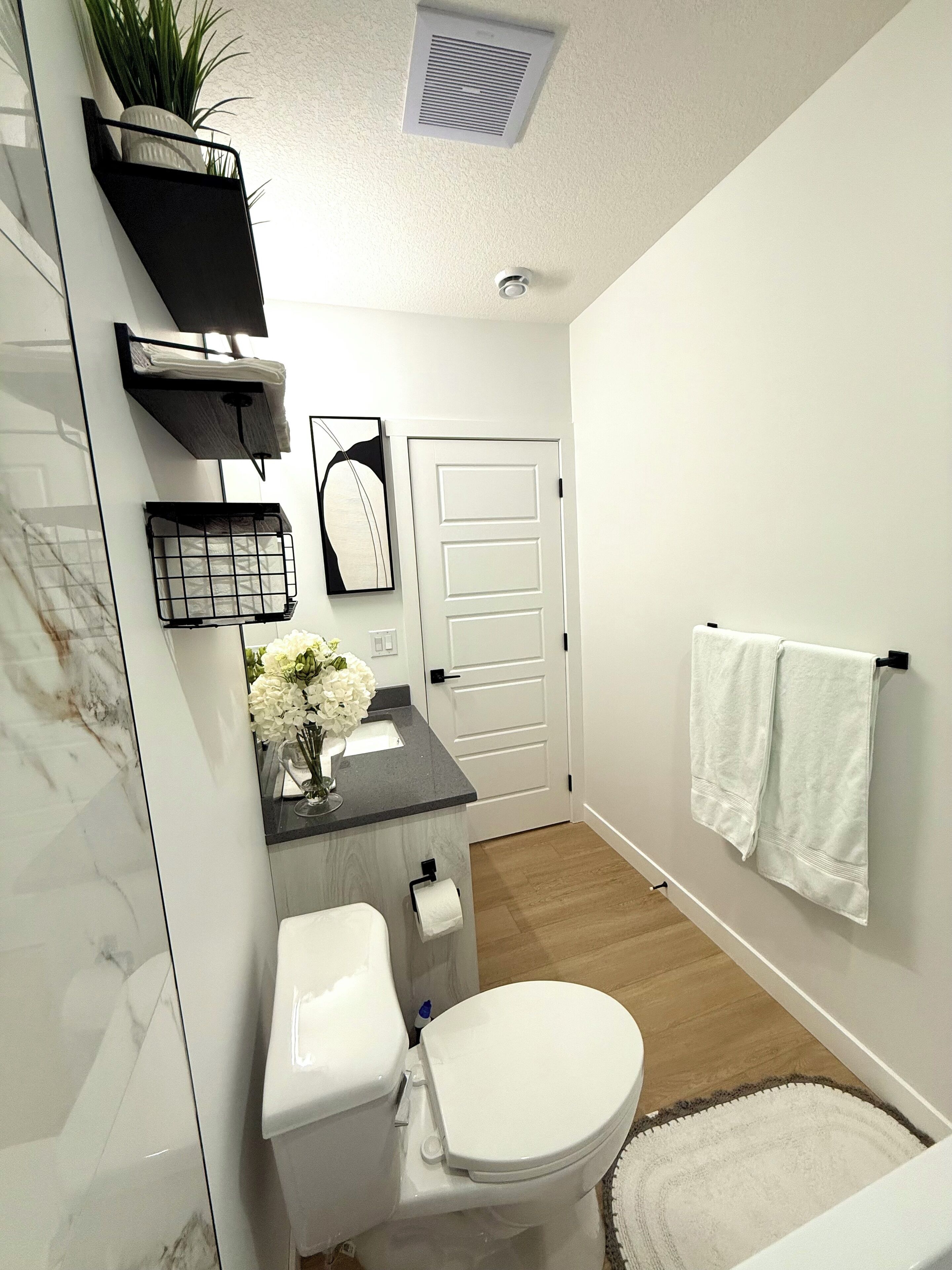 Een moderne badkamer met toilet, wastafel en handdoekhouder.