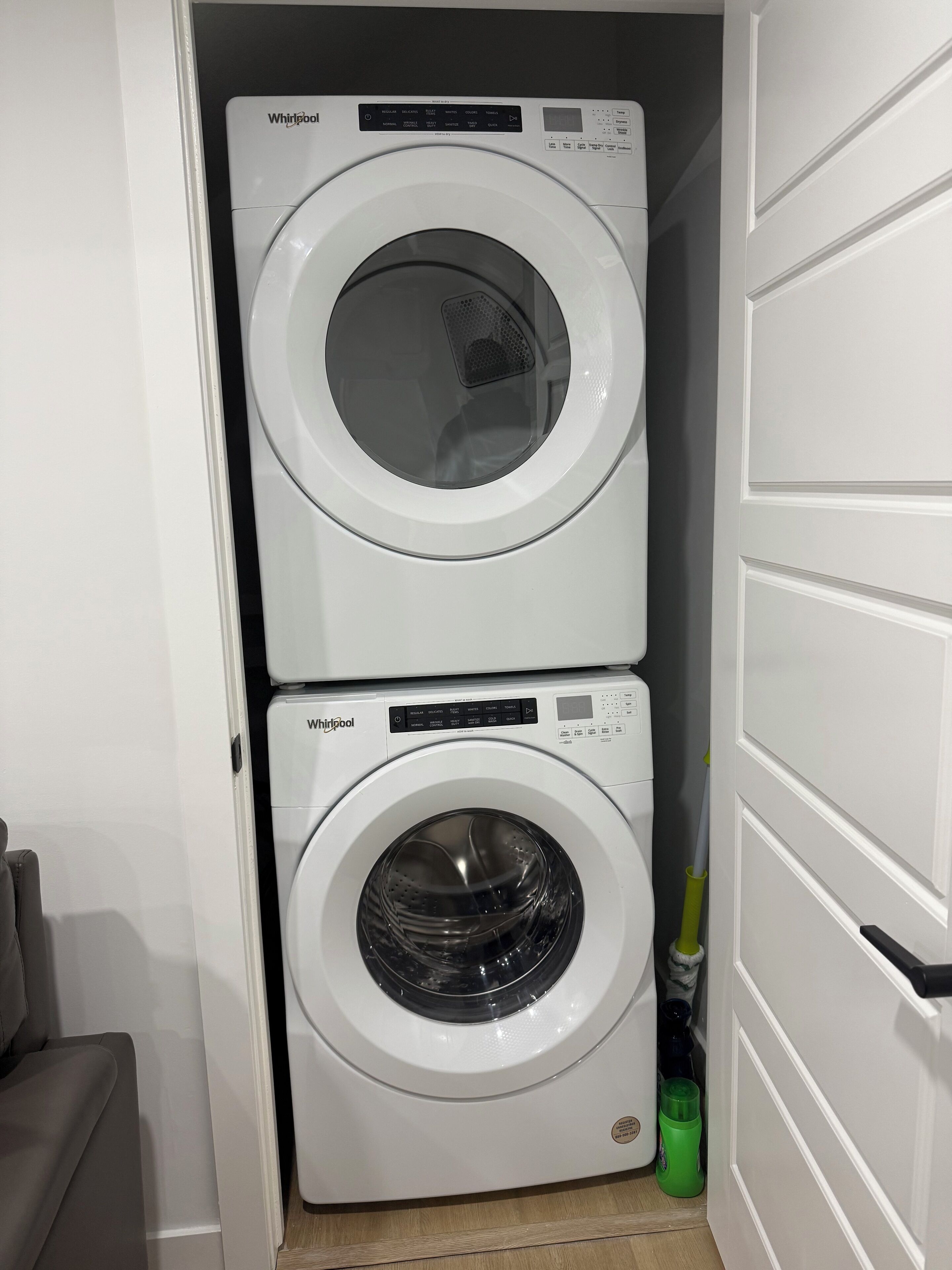 A compact laundry room with two stacked Whirlpool washing machines.
