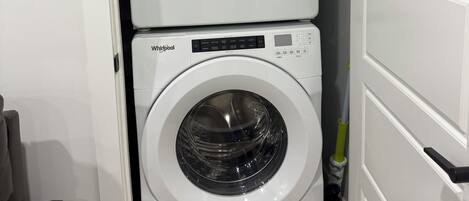 A compact laundry room with two stacked Whirlpool washing machines.