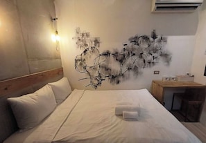 A hotel room with a bed, a wall-mounted abstract art piece, a bedside table with a lamp, and an air conditioning unit. - Heyu House Hotel (Taipei)
