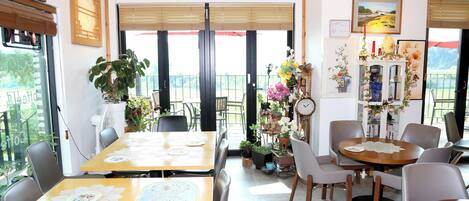 A dining area with tables and chairs, a clock, and a decorative cabinet with flowers.