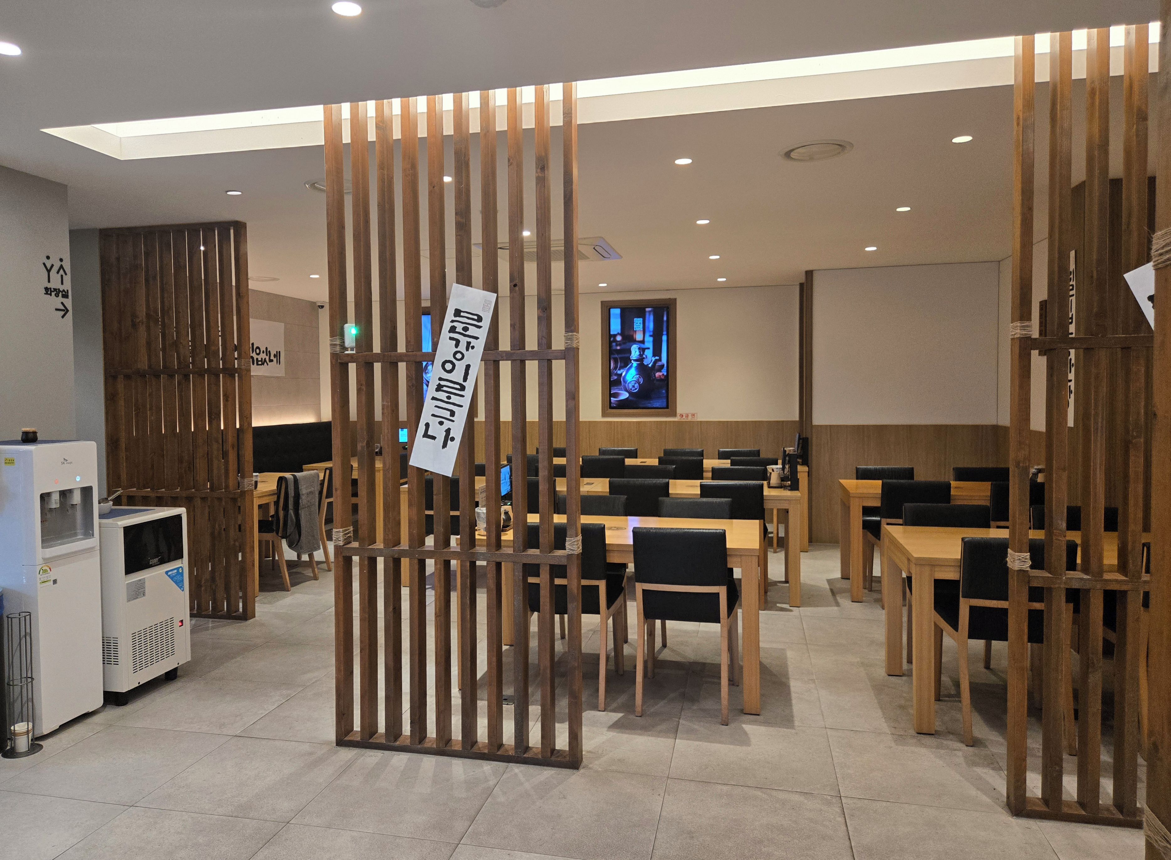 Interior modern d'un restaurant amb separadors de fusta, taules i caires.