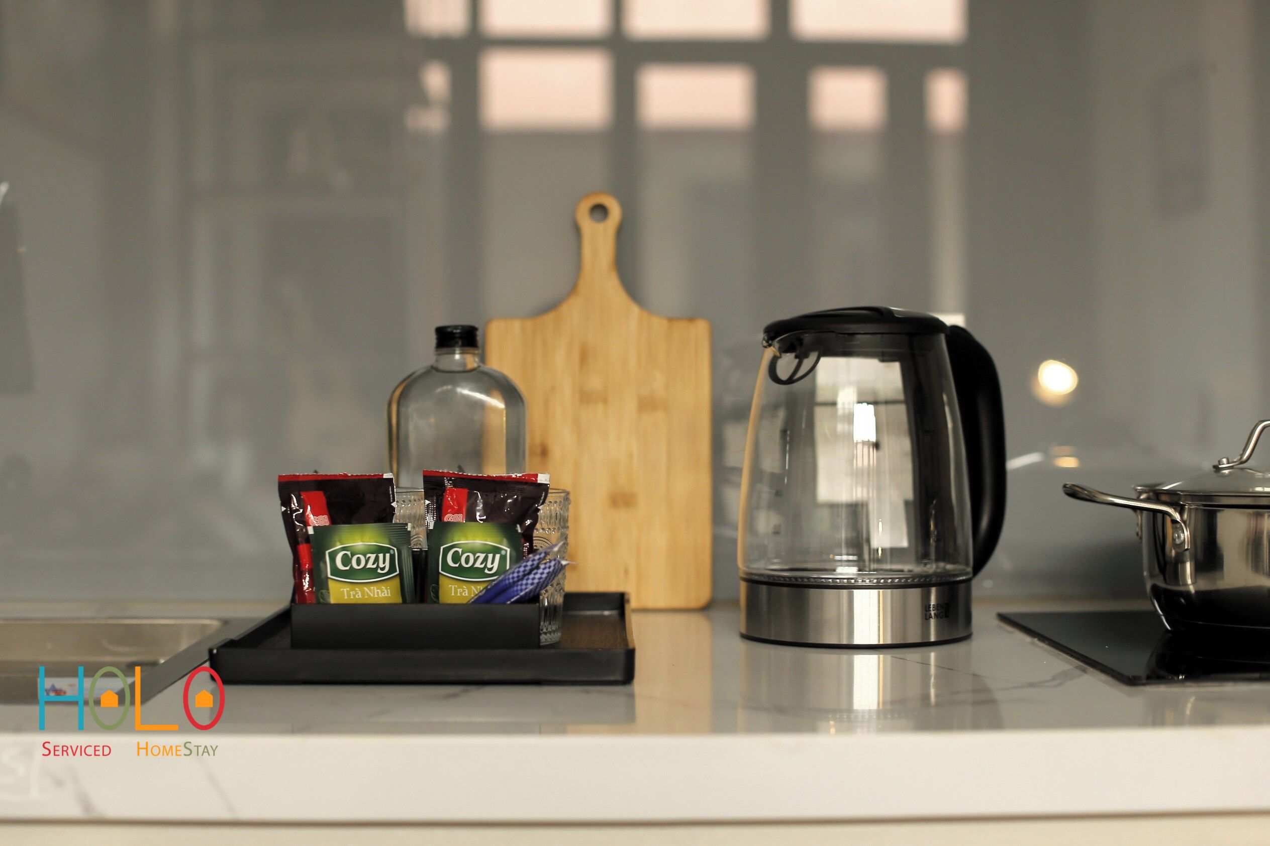 A kitchen counter with a coffee maker, a wooden cutting board, and packets of tea.