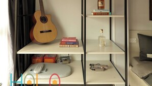 Una stanza con un letto, una chitarra, una libreria e un termosifone.