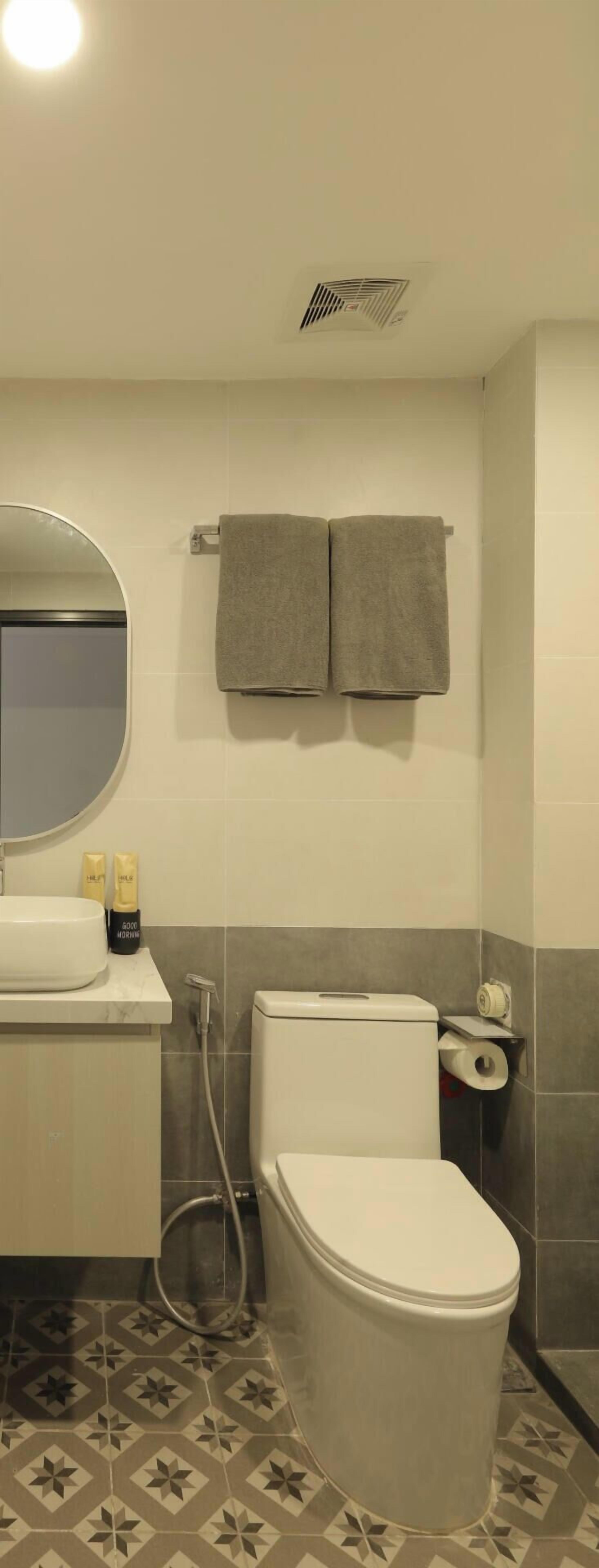 Een badkamer met toilet, wastafel, spiegel en twee handdoeken aan de muur.