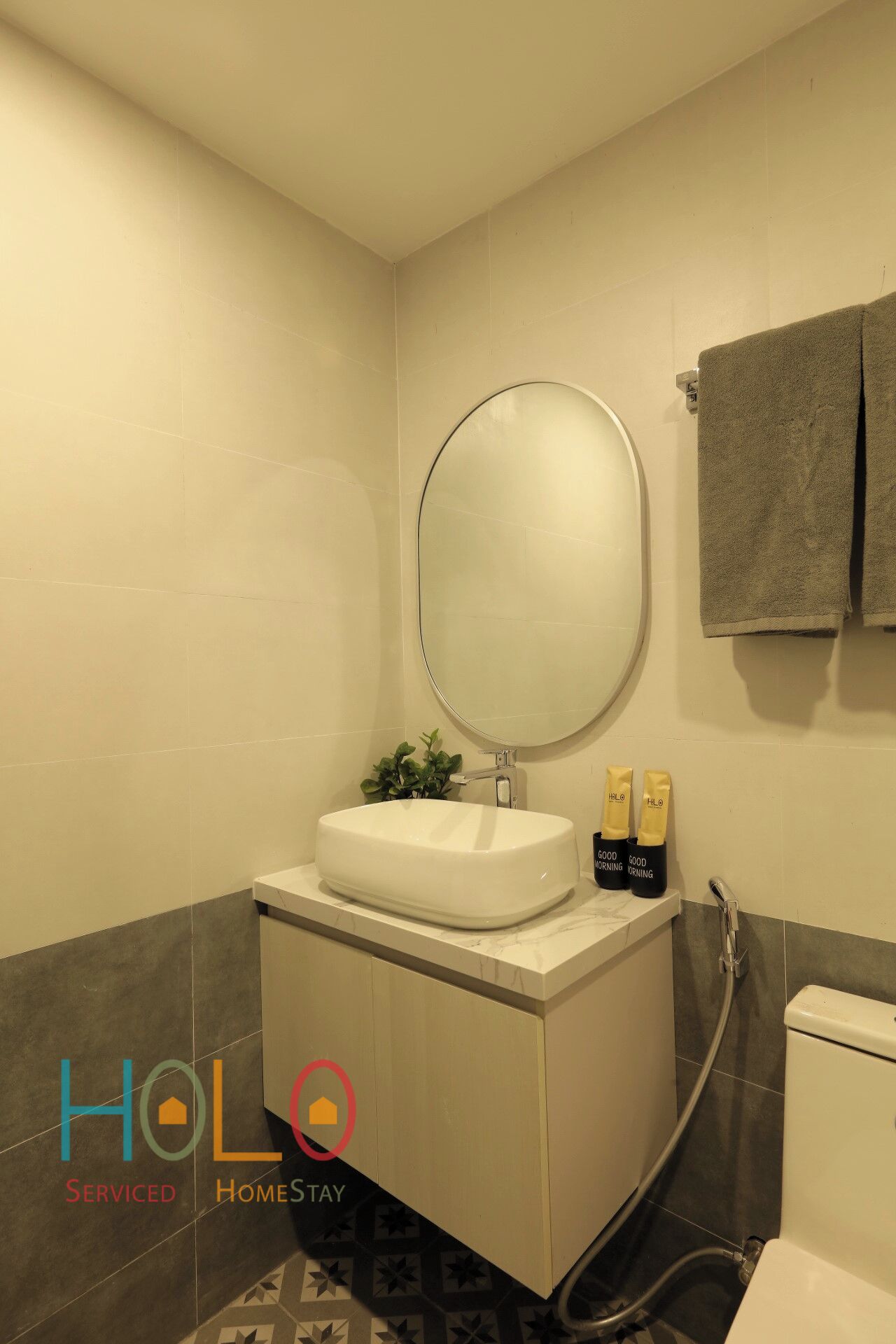 A bathroom with a white sink, a round mirror, and two towels hanging on a rack.