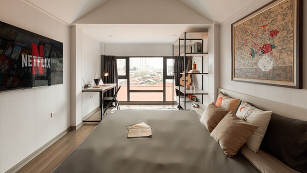 Una moderna camera d'albergo con un letto grande, una scrivania con una sedia, una libreria e un'ampia finestra vista città.