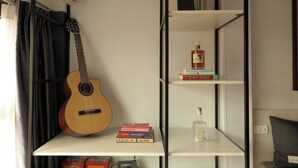 Habitació amb un llit, una guitarra, una prestatgeria i un radiador.
