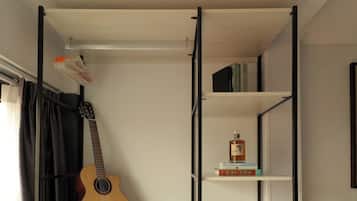 A room with a bed, a guitar, a bookshelf, and a radiator.