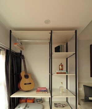 A room with a bed, a guitar, a bookshelf, and a radiator. - HoLo Ba Dinh Hanoi - Serviced HomeStay (Hanoi)