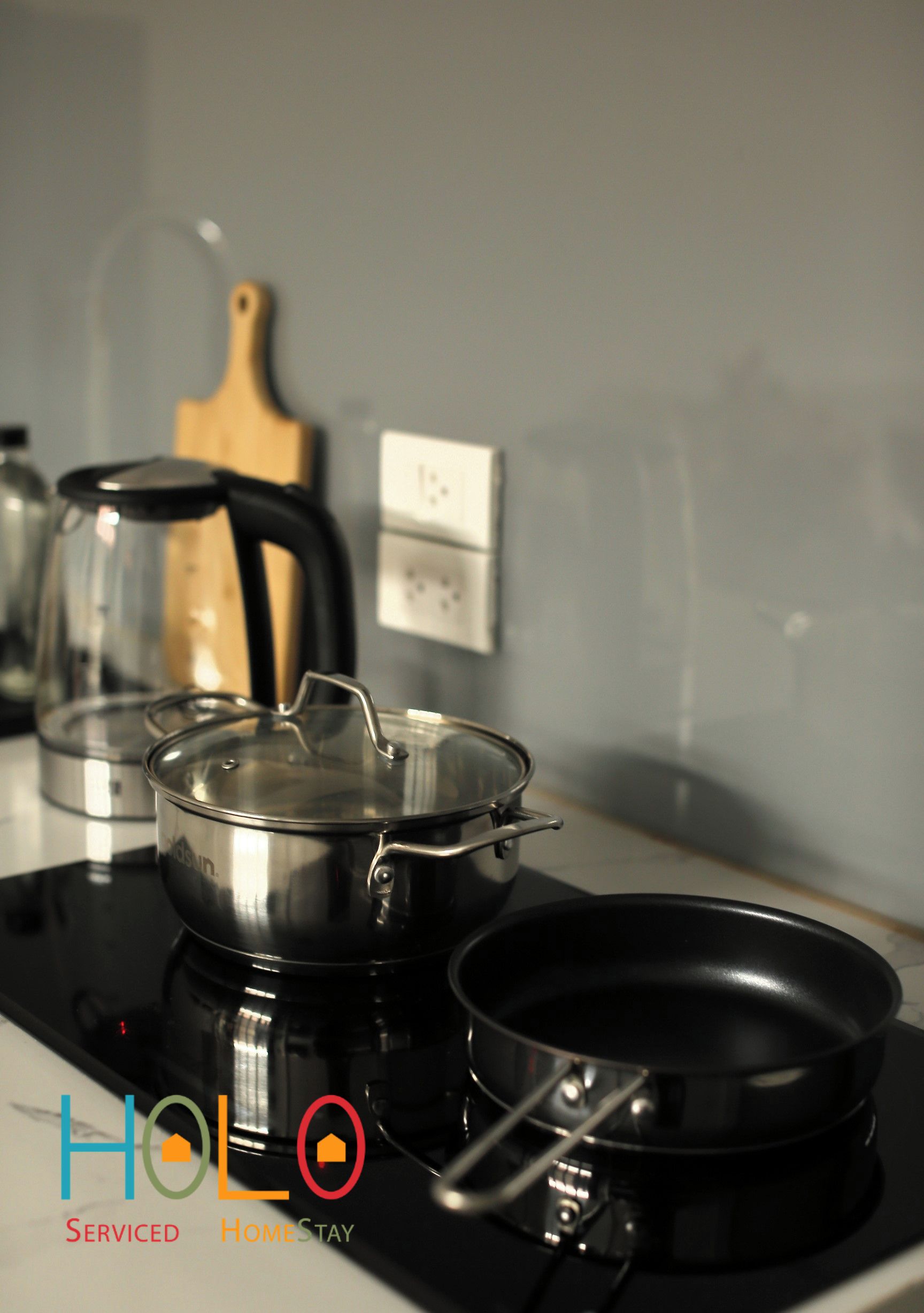 Una cocina con estufa, hervidor y tabla de cortar de madera.