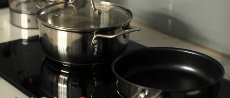 Una cocina con estufa, hervidor y tabla de cortar de madera.