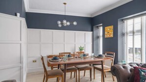 A dining area with a wooden table set for four, surrounded by wooden chairs. - Stylish Apartment with Parking, Central Ilfracombe (Ilfracombe)