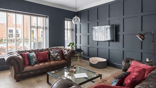 A modern living room with a leather sofa, a glass coffee table, and a mounted TV. - Stylish Apartment with Parking, Central Ilfracombe (Ilfracombe)