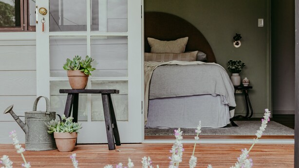 A bedroom with a bed, a nightstand, and a potted plant. - Wandarra Homestead | Luxury Country Retreat (Lue)