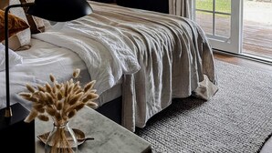 Ein Schlafzimmer mit Bett, Deckenventilator, großem Fenster und einer Tür zu einem Außenbereich.