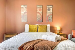 Habitación de hotel con una cama, una mesita de noche, una lámpara y arte abstracto en la pared.