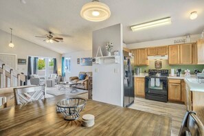 A spacious kitchen with wooden cabinets, a refrigerator, and a stove. There is a dining area with a wooden table and chairs.