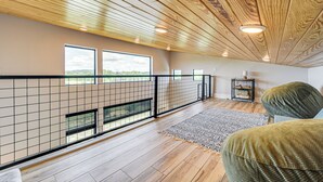 Amplia habitación con techo de madera, ventanas grandes y vistas al exterior.