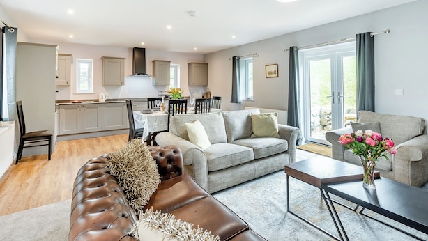 A modern living room with a sofa, coffee table, and a dining area with a table and chairs.