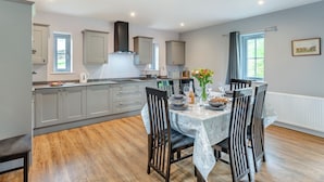 A modern kitchen with grey cabinets, a central island, and a dining area with a table set for four.