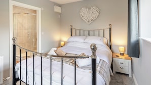 A bedroom with a bed, bedside tables, a heart-shaped wall decoration, and a curtain rod.