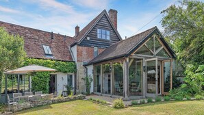 Ein traditionelles Haus mit Wintergarten, Garten und Terrassenbereich.