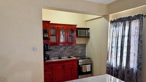 Una cocina con armarios de madera, un lavamanos de acero inoxidable, una estufa y un microondas.