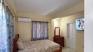 Un dormitorio con cama, cómoda, espejo y televisor.