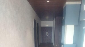 A hallway with patterned carpet, a door labeled "KITCHEN" in the distance, and a water dispenser on the right wall. - Madhurai Resort (Chikhaldara)