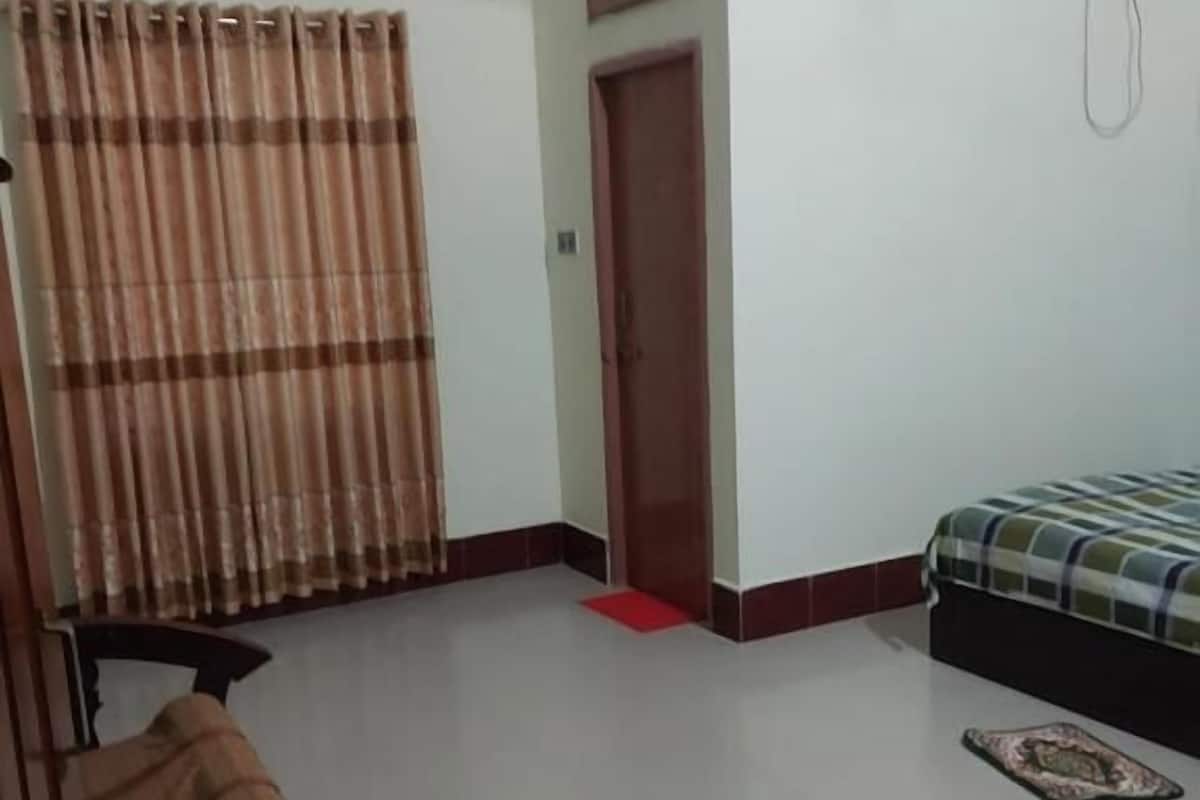A bedroom with a bed, a wardrobe, a chair, and a window with curtains.