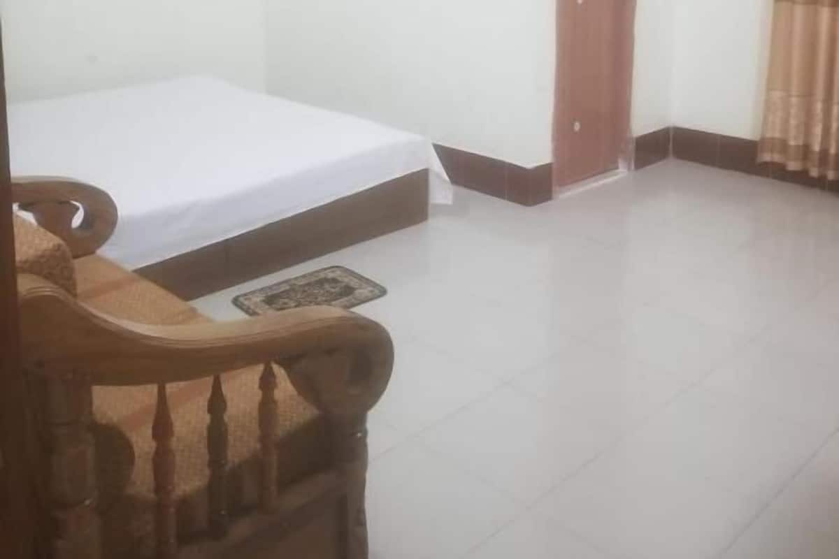 A room with a bed, a wooden chair, and a door.