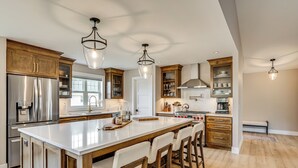 A spacious kitchen with a large island, wooden cabinets, stainless steel appliances, and pendant lighting. - Walk to Beaches + Restaurants: Elkhart Lake Escape (Elkhart Lake)