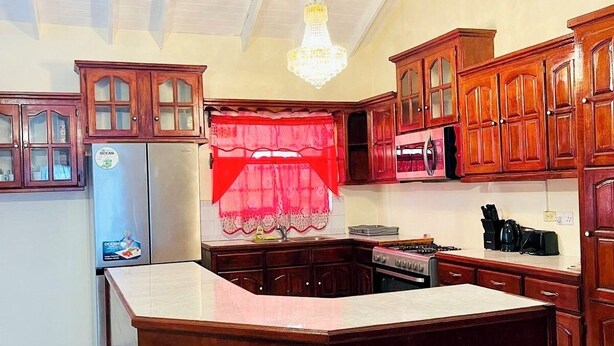 A kitchen with wooden cabinets, a central island, a refrigerator, and a chandelier.