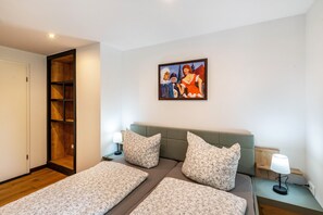A bedroom with a bed, pillows, a nightstand, a lamp, a painting, and a wooden wardrobe. - Stylish, Modern 2-Room Apartment with Shared Terrace, Garden and Wi-Fi (Bützow)